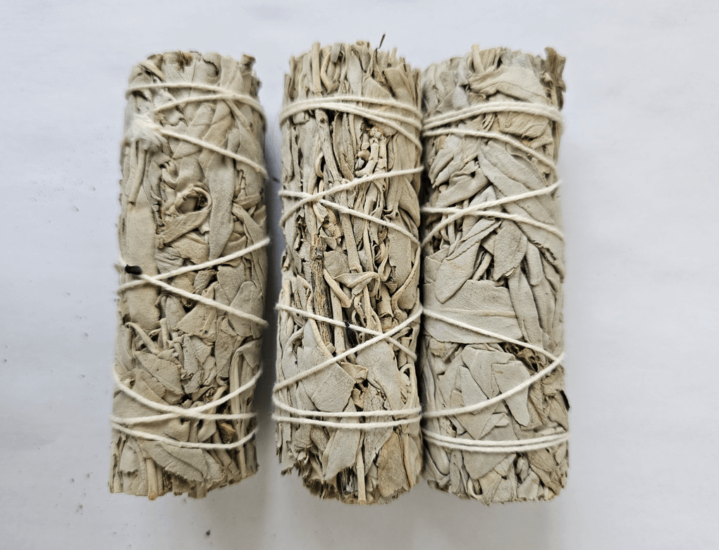 Tres ataditos de salvia blanca californiana puesta estratégicamente una al lado de otra. Están atadas con un hilo blanco