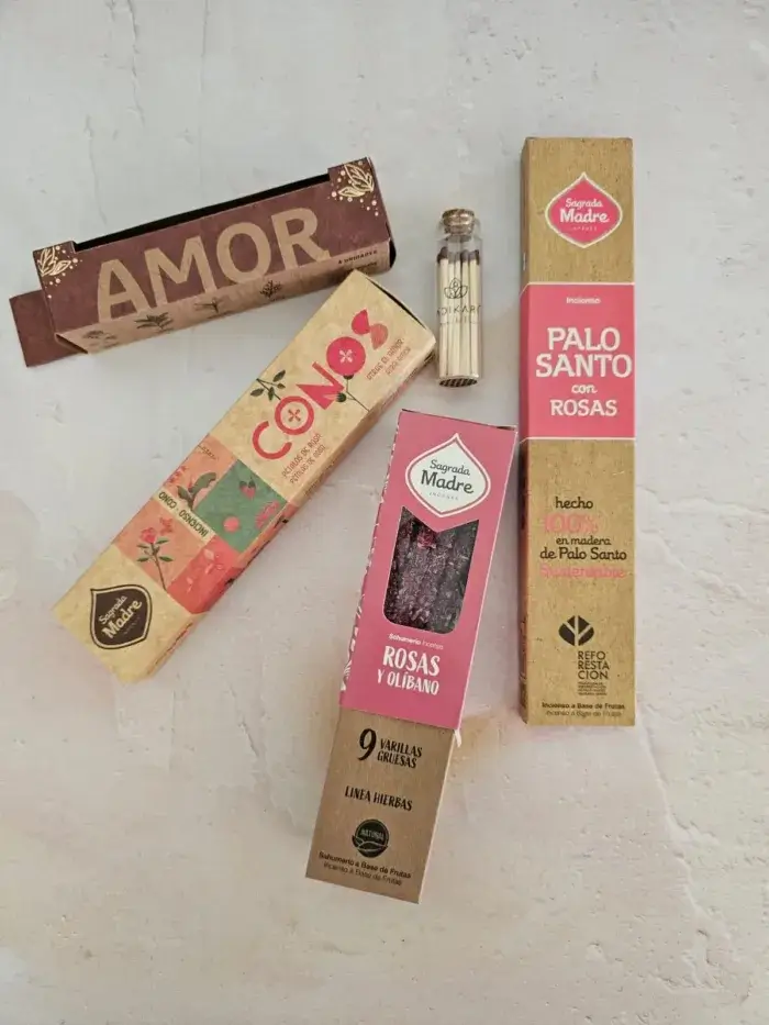 Varios cajas de inciensos artesanales, hechos a mano con rosas, olíbano y palo santo, juntos para crear un Kit Amor en Adikari. Sobre una superficie grisacea